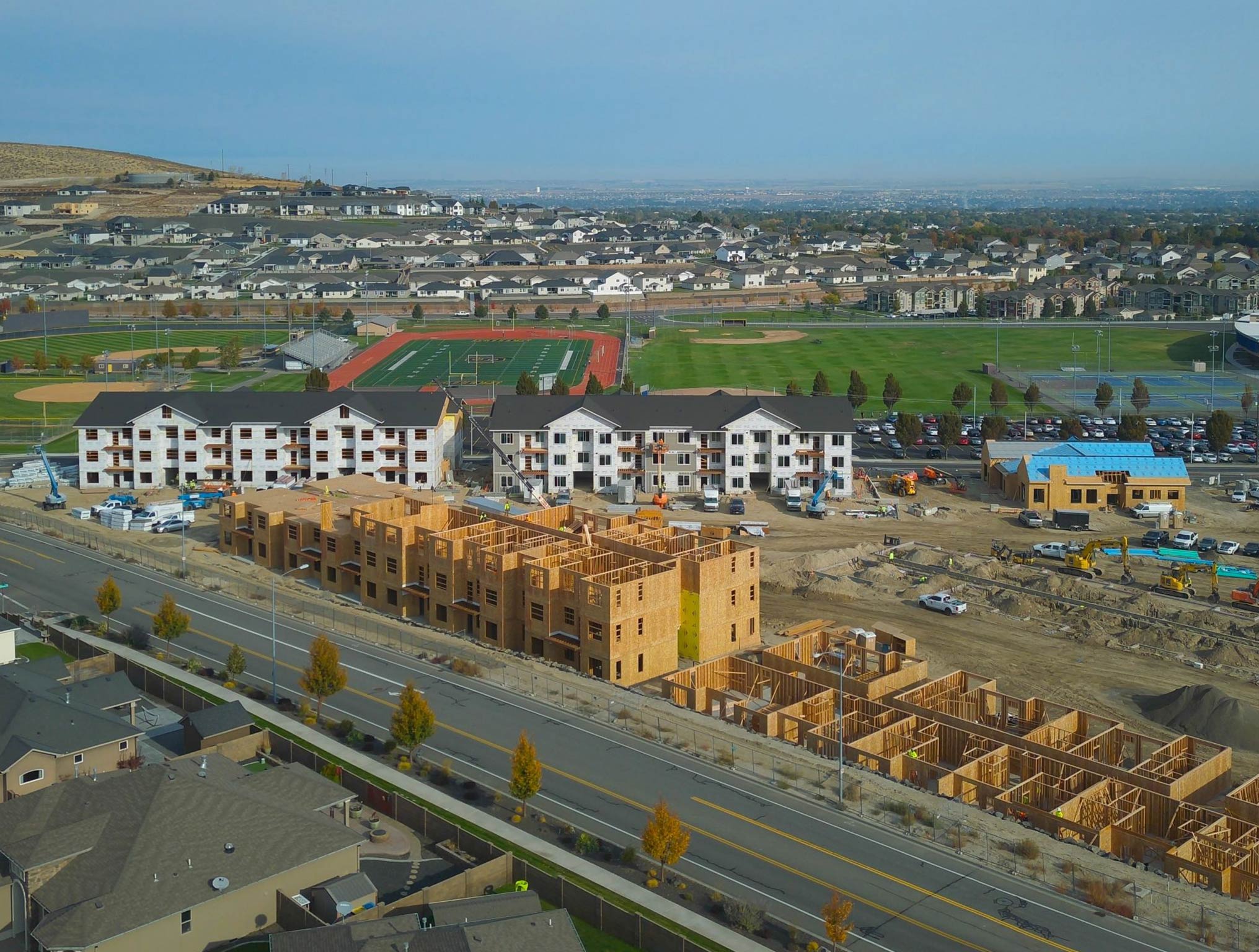 Suburban construction site with apartments and sports fields.