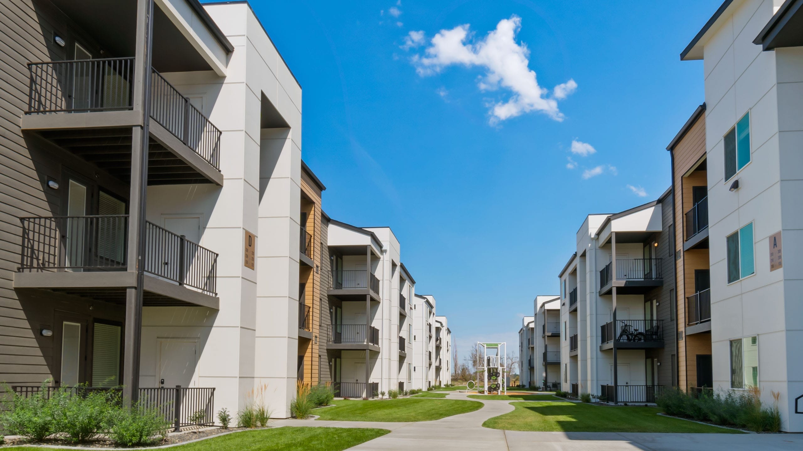 Modern apartment buildings with balconies and blue sky.