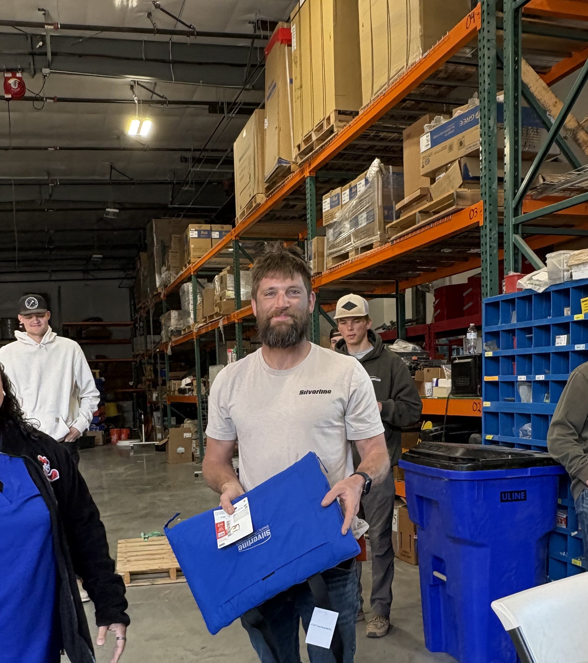 Man holding blue package in warehouse aisle