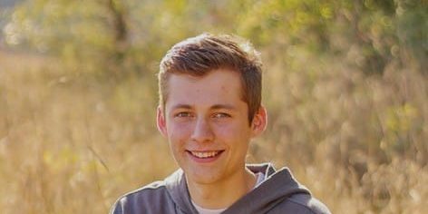 Smiling young man in gray hoodie outdoors