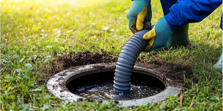 Worker cleaning outdoor drainage pipe in the yard.