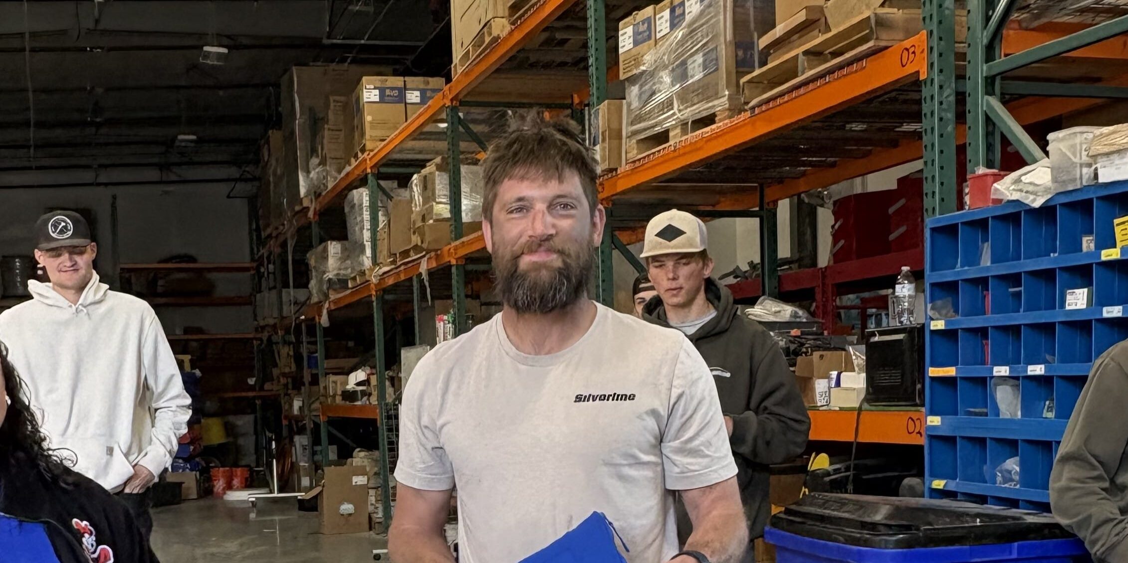Man holding blue package in warehouse aisle