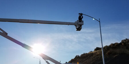 Worker repairs streetlight from crane bucket